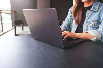 Wall Mural - Closeup image of a young woman working and typing on laptop computer