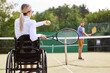 © Robert Kneschke - Inclusive tennis practice with a person using a wheelchair and partner on the court