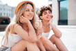 © halayalex - Two young beautiful smiling hipster female in trendy summer white t-shirt and shorts clothes. Sexy carefree women posing in the street. Positive models having fun, hugging and going crazy, sitting
