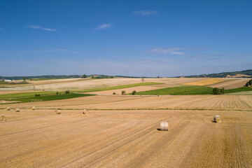 Wall Mural - Yellow golden straw bales of hay in the stubble field. Hay bales on agriculture field after harvest on a sunny summer day