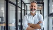 © JINGWEN - Smiling handsome businessman with crossed arms in modern office, middle-aged gray-haired man exuding confidence, business success concept.