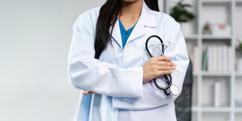 Confident Female Doctor in White Coat Holding Stethoscope in Modern Medical Office