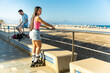 © Alfonso Soler - Multiracial couple roller skating on the beach in Spain