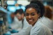 © Harvinder - Happy black biochemist working with her colleagues in lab and looking at camera, Generative AI