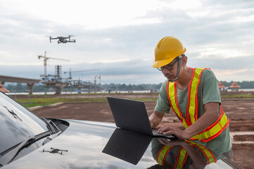 Asian engineers inspect a construction project of a Thailand-Laos Mekong River bridge using a drone to get an aerial view of the bridge.