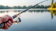 © JP STUDIO LAB - A close-up of a hand holding a fishing rod, with the line cast into a calm lake