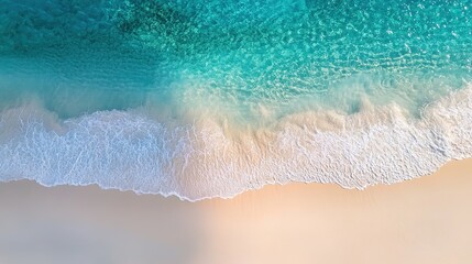 Gentle wave rolls onto sandy beach from turquoise sea