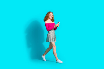 Wall Mural - Full body portrait of lovely young girl walk use phone wear top isolated on turquoise color background