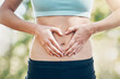 © Hira/peopleimages.com - Heart, woman and hands on stomach for fitness, body and wellness outdoor. Abdomen, love and sign for care, digestion or gut health with intermittent fasting to lose weight with hcg diet detox at park