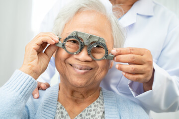 Optometrist checking Asian elderly woman ophthalmic vision eye test and using optical trial frame.