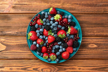 Wall Mural - Mix of ripe colorful berries in bowl photography . Blueberry , strawberry , raspberry , blackberry and red currant . Top view