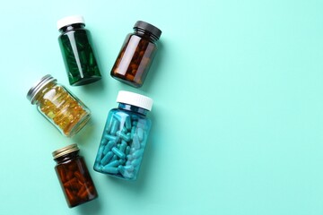 Canvas Print - Pharmacist. Different pills in plastic bottles on light blue background, flat lay. Space for text