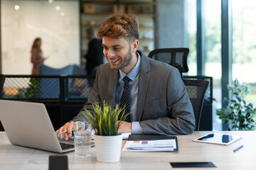 Wall Mural - Portrait of young man sitting at his desk in the office.