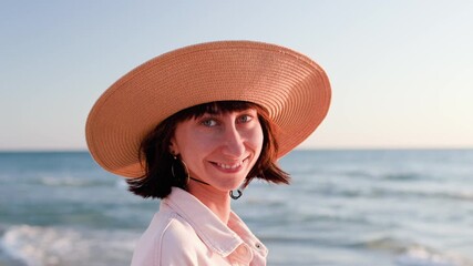 Wall Mural - cheerful mood. a young and cheerful girl in a hat posing on the beach in the sunset light.