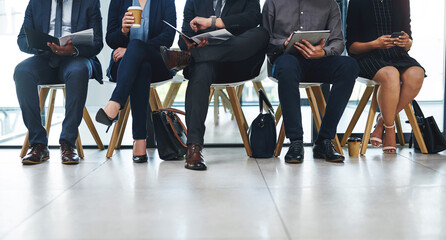 Canvas Print - Business people, legs and group in waiting room for interview, hiring opportunity and job search. Chairs, queue and feet of candidates in office for hr meeting, recruitment and onboarding process