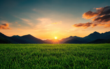 Wall Mural - Breathtaking sunset over lush green field with majestic mountains in the background, under a vibrant, colorful sky.