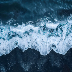 Wall Mural - Aerial drone view or top view perspective photography of a beautiful transparent clear sea or ocean waves and foam splashing on the dark navvy blue or gray sand beach. 