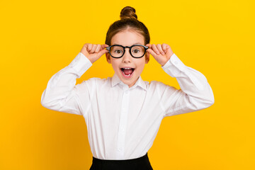 Wall Mural - Photo of cute schoolgirl open mouth touch spectacles wear uniform isolated on yellow color background