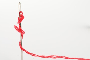 Poster - Sewing needle with red thread isolated on white, closeup