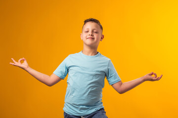 Kid boy smiling peacefully holding his fingers in mudra gesture, meditating. Zen, meditation, consciousness, balance and peace concept.