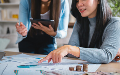 Fototapete - Two women are looking at a piece of paper with a pie chart on it