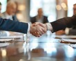 © MaVeRa - Businessmen shake hands to close a deal on the background of a round table with colleagues, bokeh effect