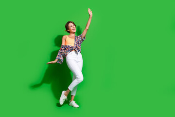 Canvas Print - Full size photo of cheerful girl wear print shirt waving palm say hellow look at her friend empty space isolated on green color background