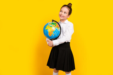 Sticker - Photo of cute schoolgirl hold globe look empty space wear uniform isolated on yellow color background