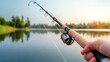 © JP STUDIO LAB - A close-up of a hand holding a fishing rod, with the line cast into a calm lake