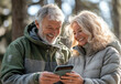 © HAMNA - Romantic older couple with smartphone relaxing on bench In summer park, senior couple concept.