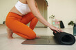 © DragonImages - Person kneeling on floor while preparing yoga mat for workout session showing focus and determination while getting ready for exercise in indoor space