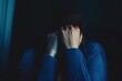 © Matt - Woman in a dark room covering her face with hands, expressing fear and anxiety, highlighted by moody, dramatic lighting