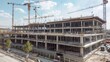 © peerawat - A partially built shopping mall with scaffolding and cranes, hinting at the commercial growth in the area.