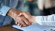 © Pinklife - This image captures a close-up of two individuals shaking hands, symbolizing a business agreement or deal. They appear to be sealed in a professional setting.