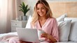 © Pinklife - A woman dressed in pink pajamas, sitting comfortably in bed, using her laptop and enjoying a cup of coffee in the morning, surrounded by a cozy bedroom ambiance.