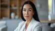 © Najikung - A confident businesswoman poses in a modern office, showcasing professionalism and elegance with a calm demeanor and stylish attire.