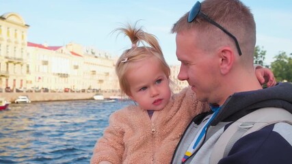 Wall Mural - A father holds a child's daughter in his arms and walks in the center of St. Petersburg, the tourist summer season.