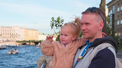 Wall Mural - A father holds a child's daughter in his arms and walks in the center of St. Petersburg, the tourist summer season.