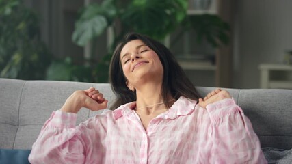 relaxed woman stretching on cozy sofa in home