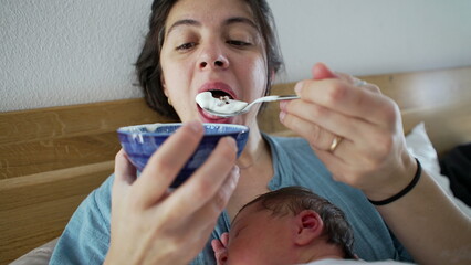 Mother holding bowl of yogurt while newborn baby sleeps on her chest, multitasking parent enjoying snack time, cozy indoor setting, intimate family moment, combining care and nourishment