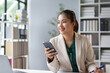 © Crystal - Businesswoman is smiling while holding a smartphone in her office, suggesting a positive and productive work environment