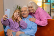 © Andrii Iemelianenko - Caucasian grandfather, grandmother and small granddaughter making video call online on smartphone at home. Girl with grandparents talking by internet webcam chat app sitting on sofa in living room.