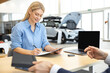 © zinkevych - Happy woman signing contract for the purchase of car in showroom
