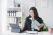 © Crystal - Businesswoman smiling and comparing information between a digital tablet and a notebook while sitting at her desk