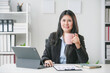 © Crystal - Smiling asian businesswoman drinking coffee while working on a project on a digital tablet in her office