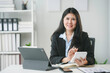 © Crystal - Smiling asian accountant woman calculating and analyzing financial data on digital tablet and financial chart at her office desk