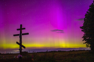 night starry sky outside the city with purple reflections of the northern lights