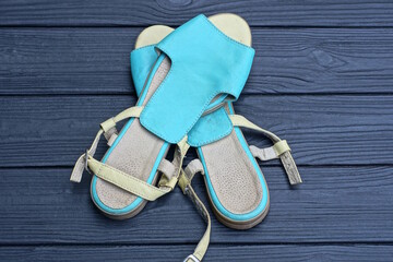 two blue gray leather summer sandals stand on a black wooden table