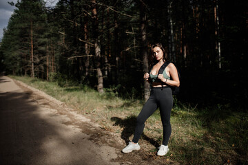 woman in sportswear in the forest with a backpack