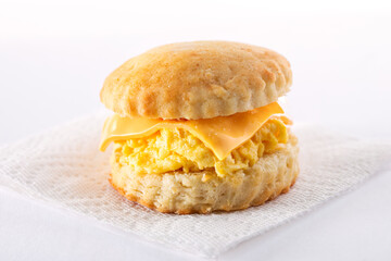 Homemade scrambled egg and cheese biscuit on a white napkin and white background; copy space